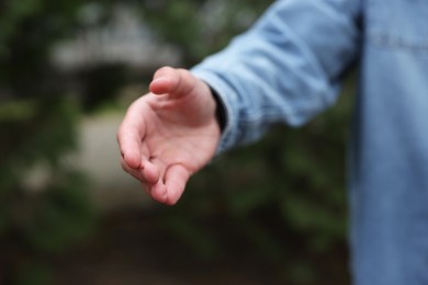 Photo of Offering help. Man reaching his hand outdoors, closeup