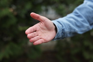 Photo of Offering help. Man reaching his hand outdoors, closeup