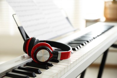 Photo of Synthesizer with music sheets and headphones indoors, closeup