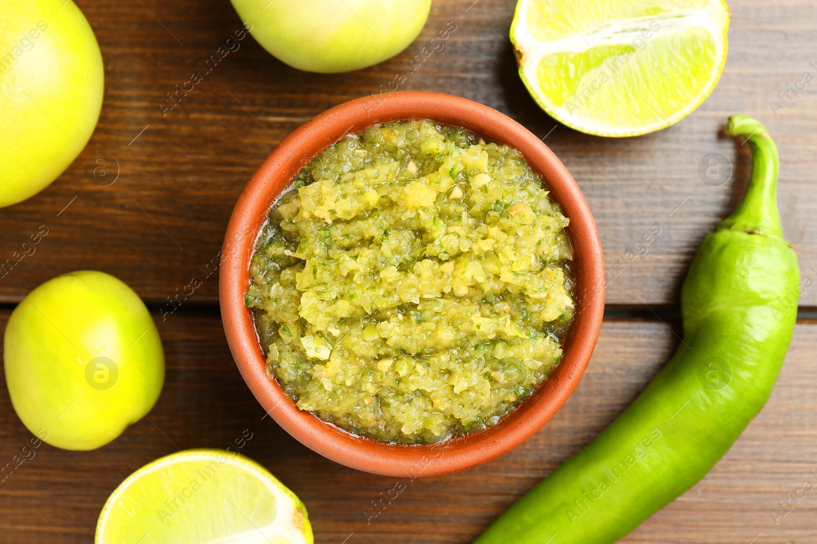 Photo of Delicious salsa sauce in bowl and products on wooden table, flat lay