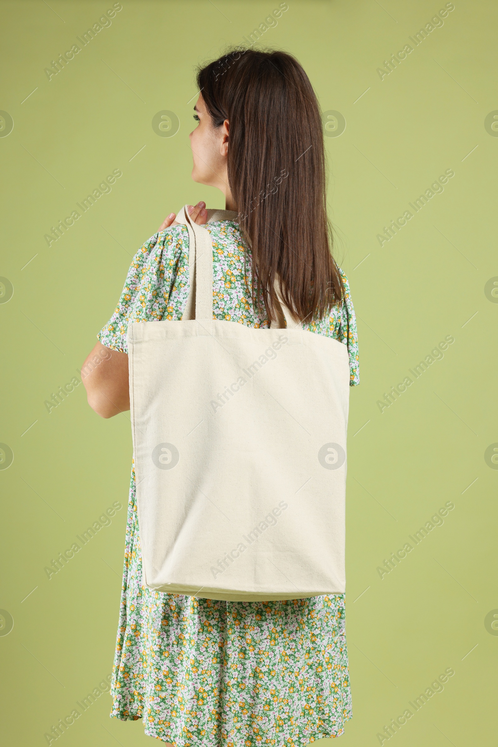 Photo of Woman with blank shopper bag on color background, back view. Mockup for design