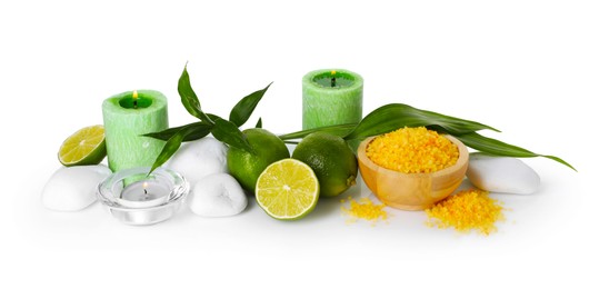 Photo of Spa composition with limes, massage stones, burning candles, sea salt and green leaves isolated on white