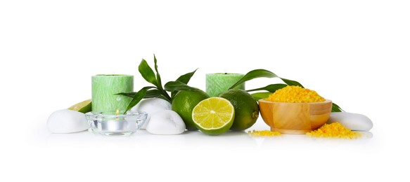 Photo of Spa composition with limes, massage stones, burning candles, sea salt and green leaves on mirror surface against white background