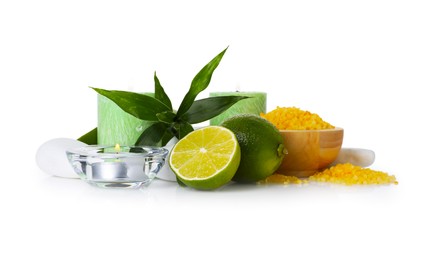 Photo of Spa composition with limes, massage stones, burning candles, sea salt and green leaves on mirror surface against white background