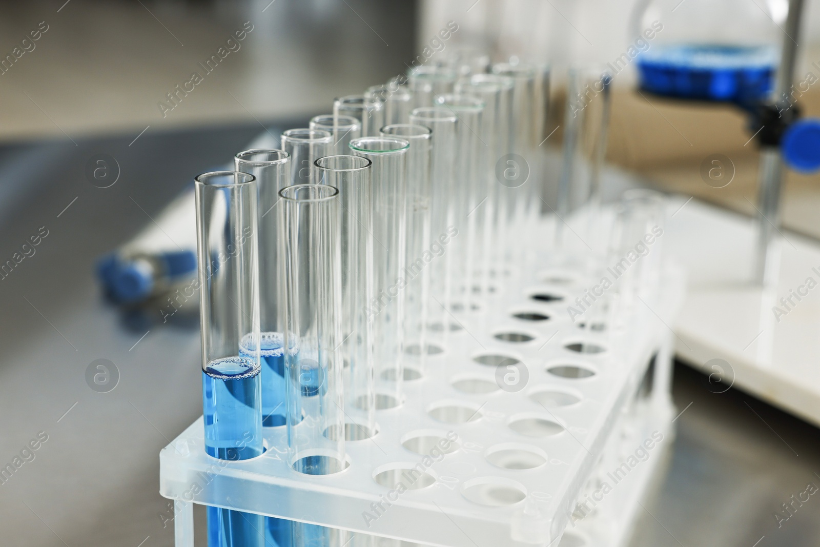 Photo of Test tubes with blue liquid on table in laboratory, closeup