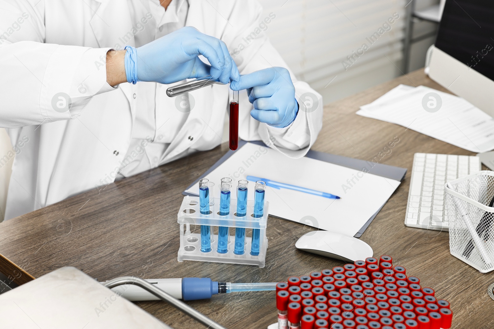 Photo of Scientist with test tubes working at table in laboratory, closeup