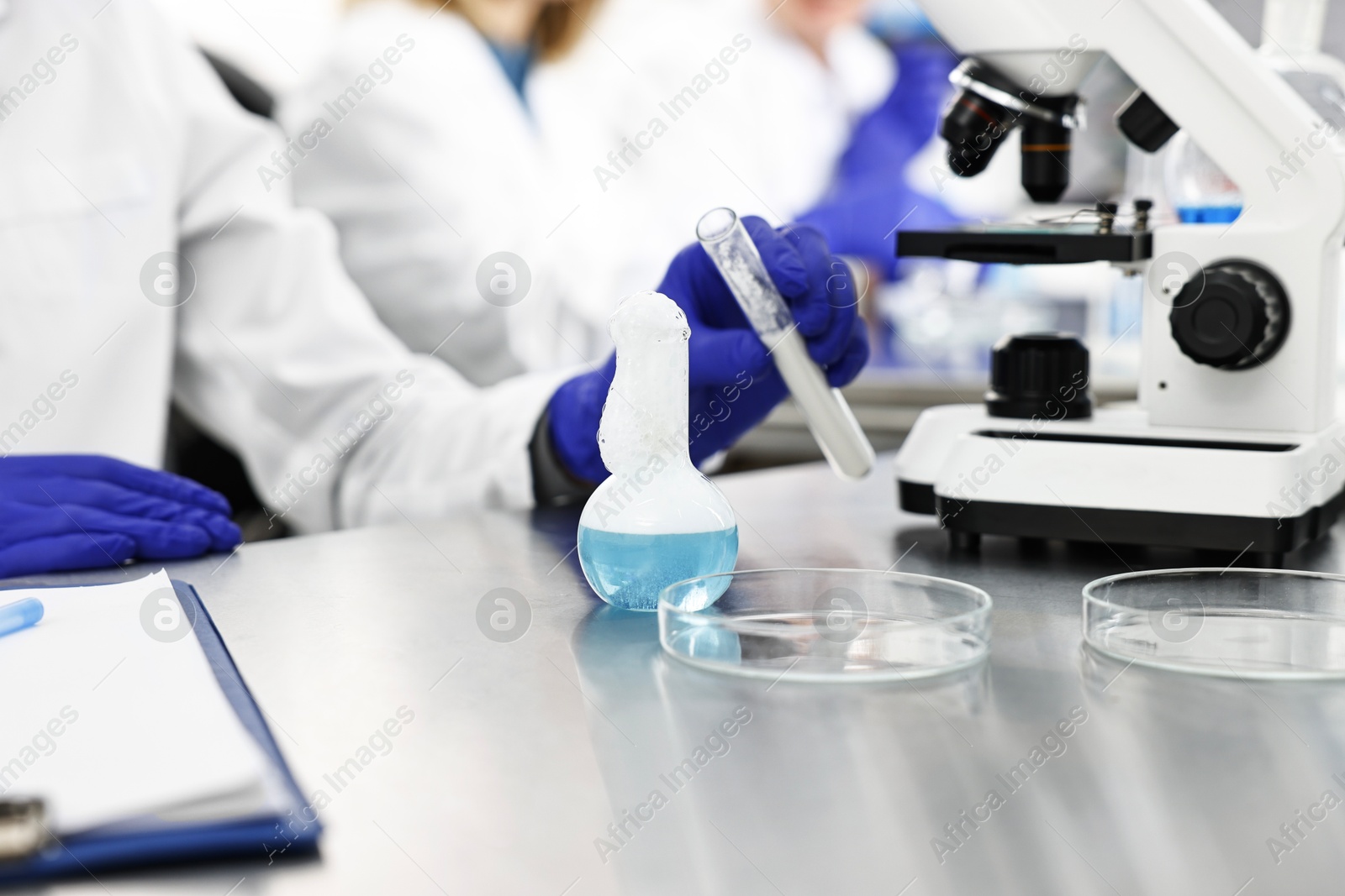 Photo of Scientist with test tube and flask working in laboratory, closeup