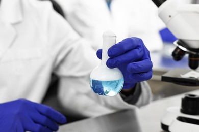 Photo of Scientist with flask working at table in laboratory, closeup