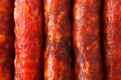 Photo of Many tasty smoked sausages as background, top view