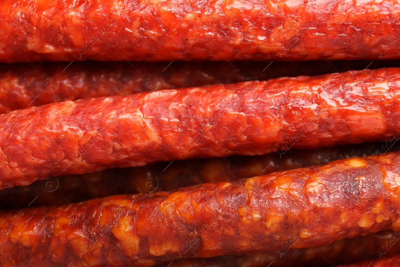 Photo of Many tasty smoked sausages as background, top view