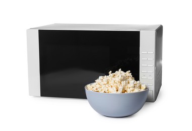 Photo of Bowl of popcorn and microwave oven isolated on white