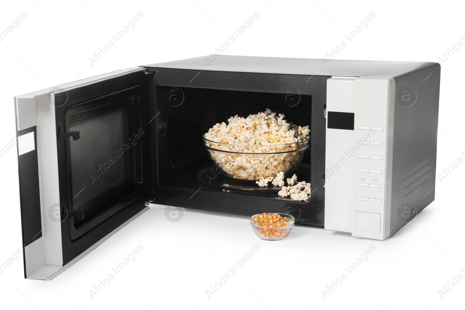 Photo of Open microwave oven with bowl of popcorn and kernels isolated on white