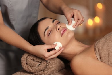 Photo of Young woman receiving facial massage with spa stones in salon