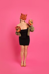 Photo of Quadrobics. Woman wearing fox mask and gloves on pink background