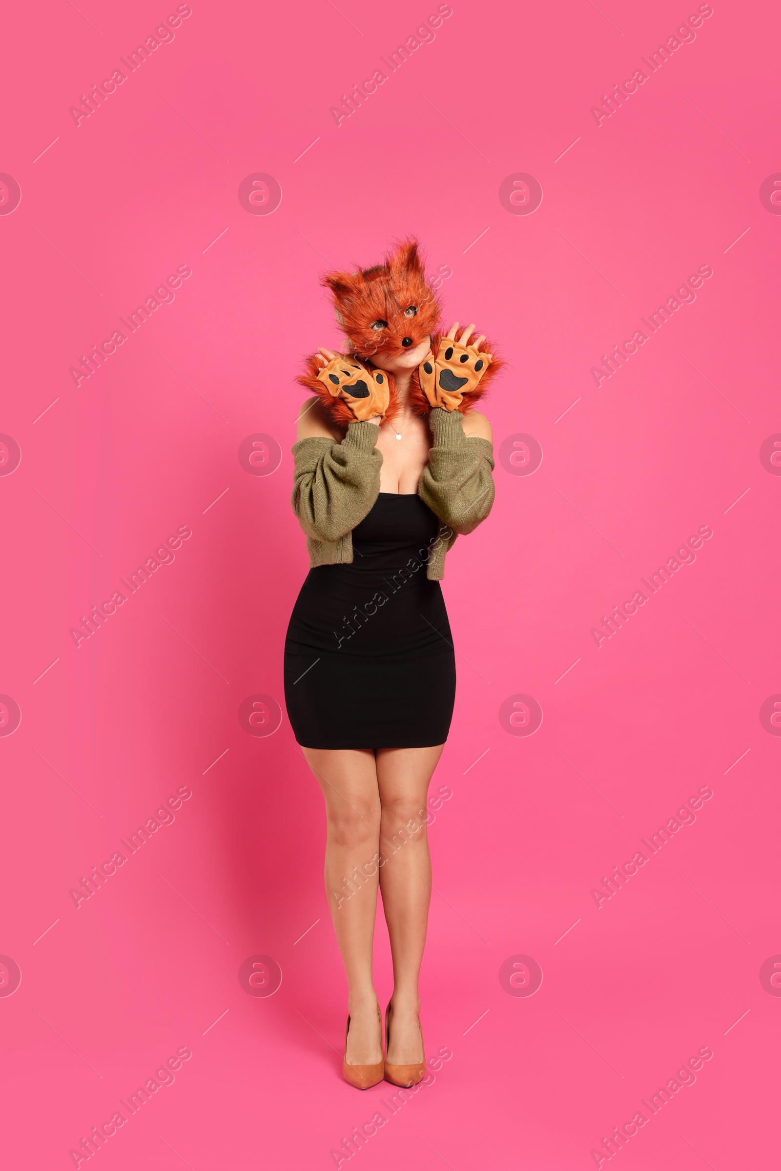 Photo of Quadrobics. Woman wearing fox mask and gloves on pink background