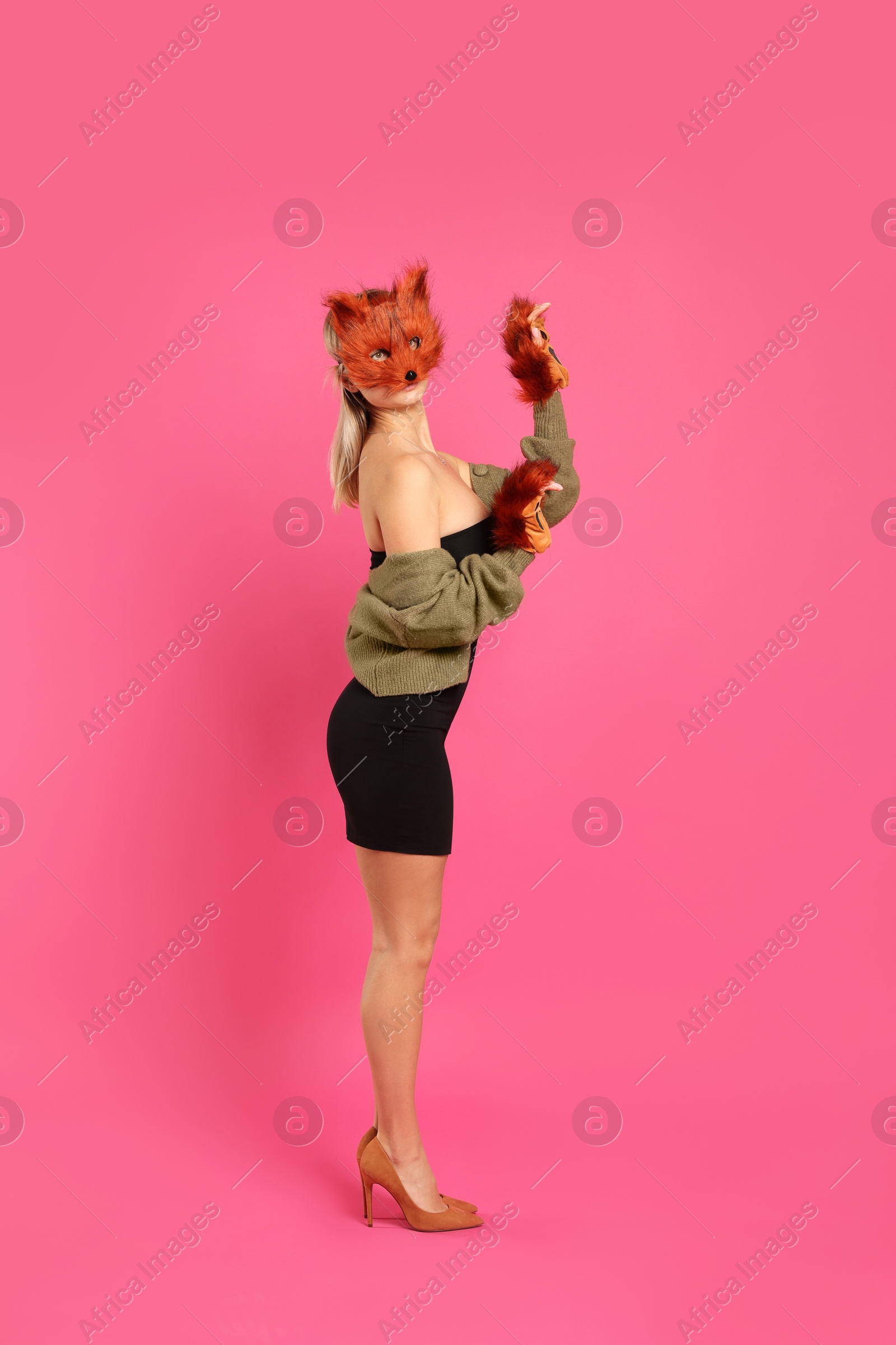 Photo of Quadrobics. Woman wearing fox mask and gloves on pink background