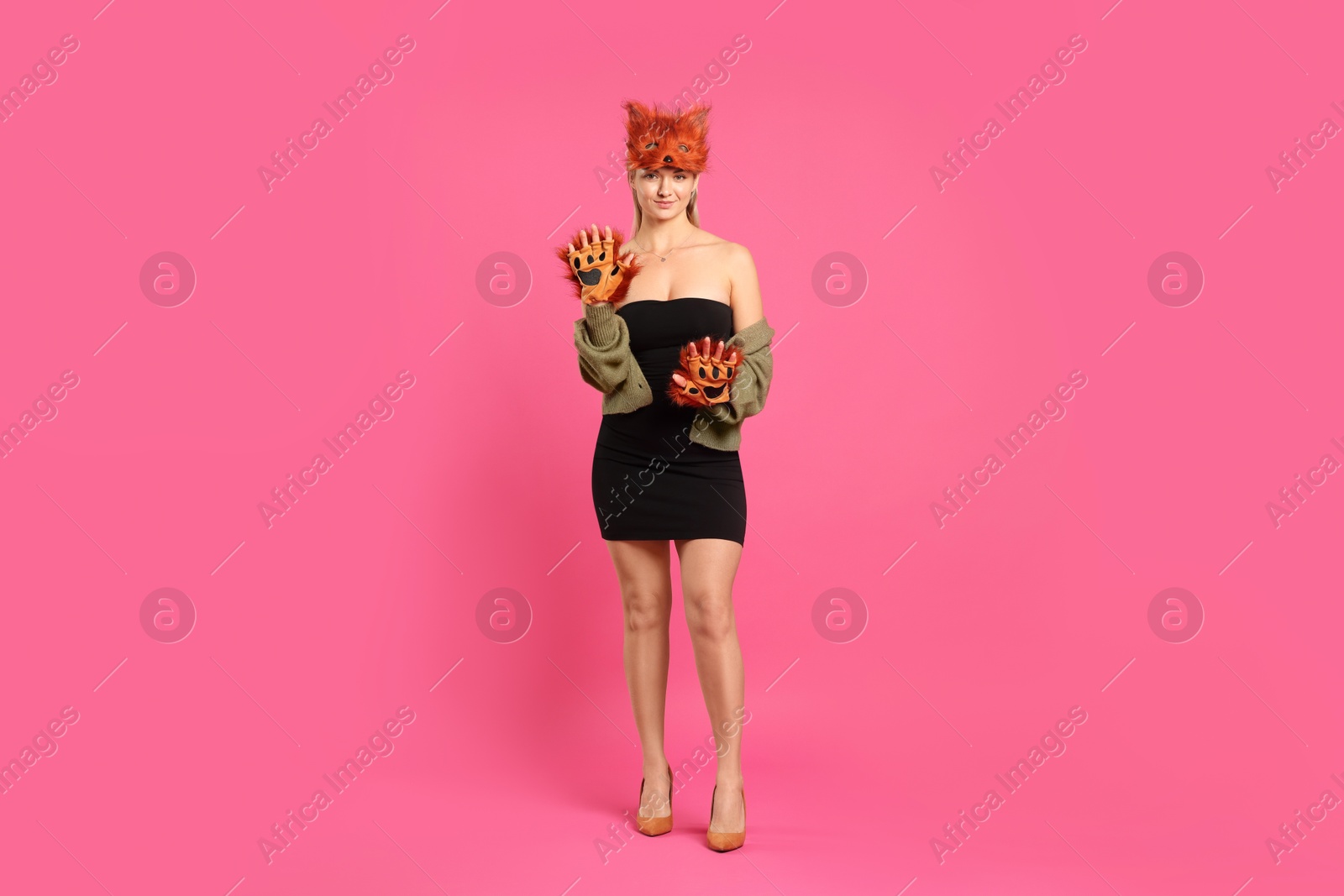 Photo of Quadrobics. Woman wearing fox mask and gloves on pink background