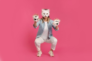 Photo of Quadrobics. Woman wearing cat mask and gloves on pink background