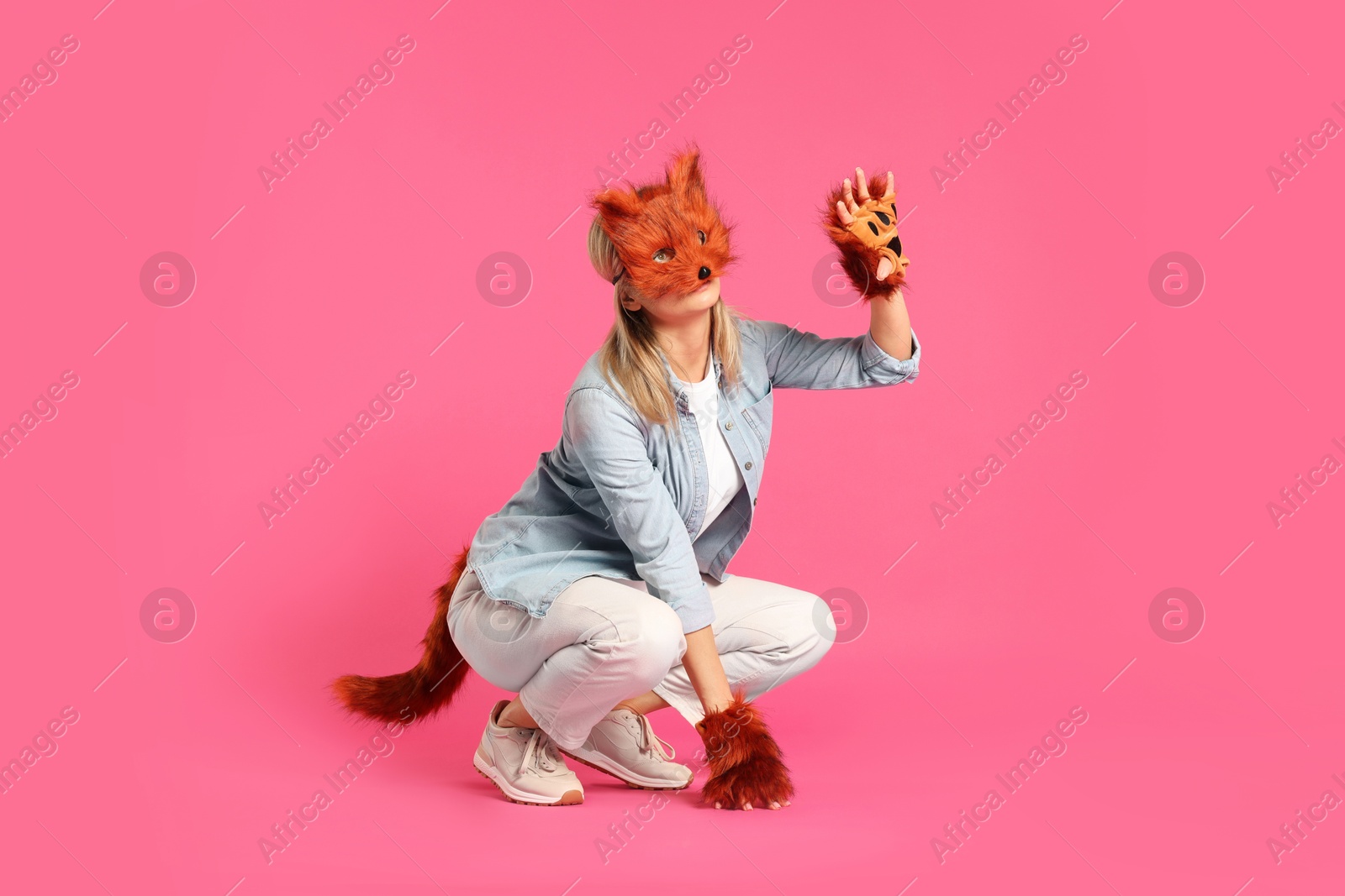 Photo of Quadrobics. Woman wearing fox mask, gloves and tail on pink background