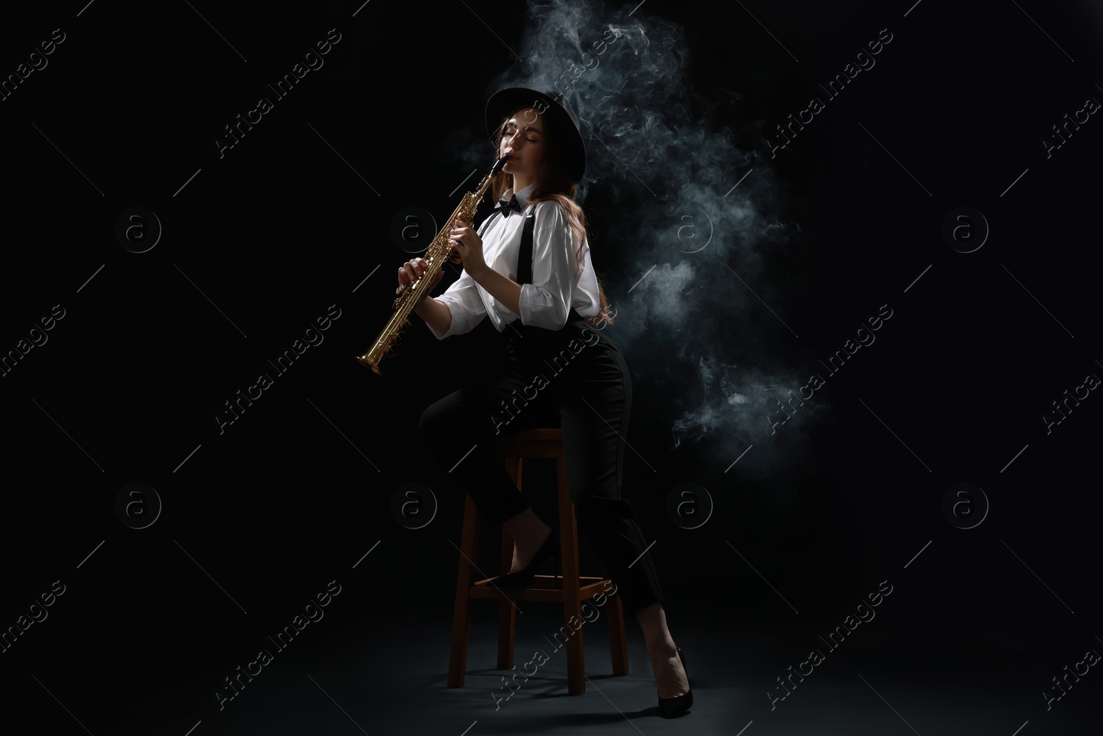 Photo of Musician playing soprano saxophone on dark background with smoke