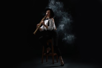 Photo of Musician playing soprano saxophone on dark background with smoke