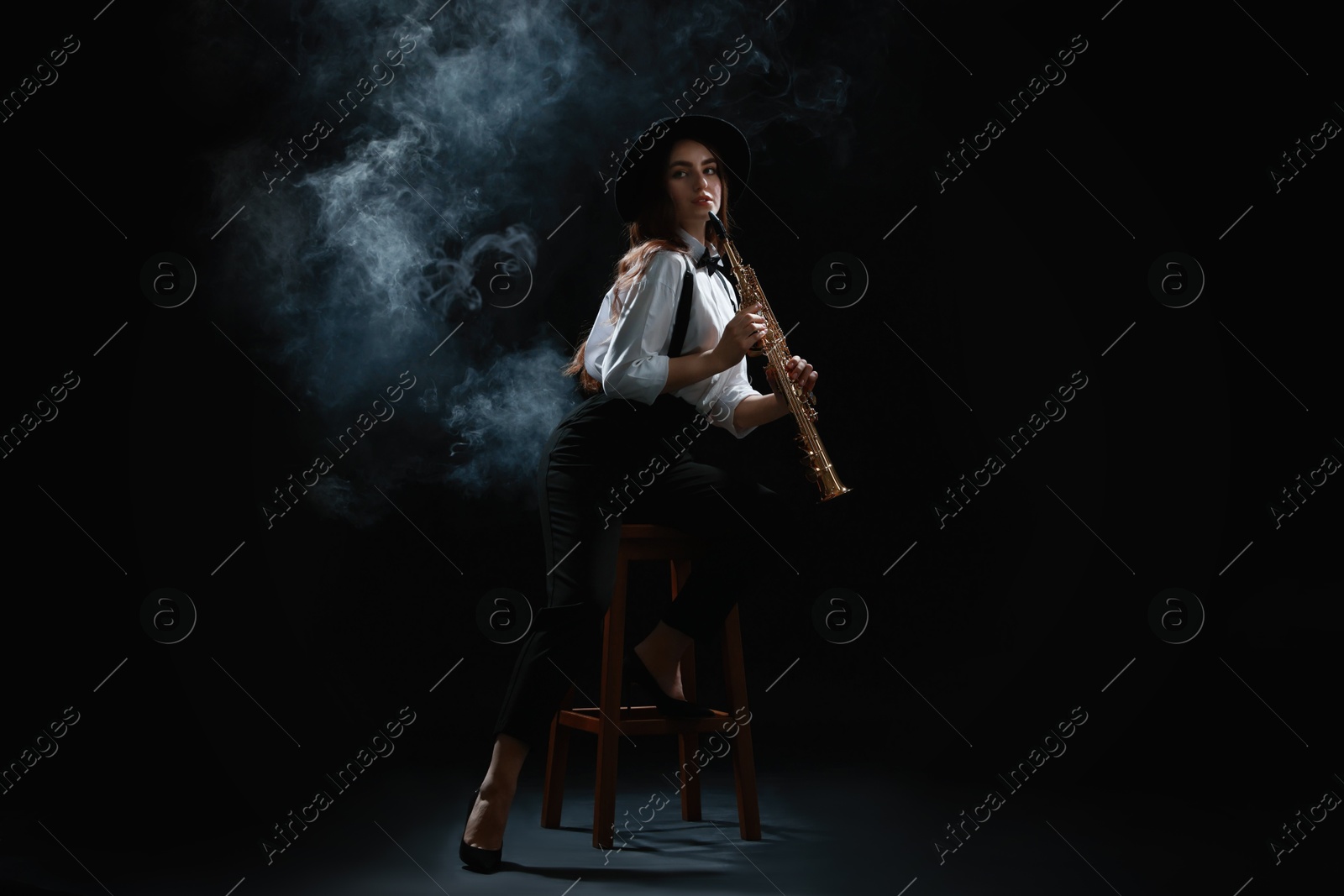 Photo of Musician playing soprano saxophone on dark background with smoke