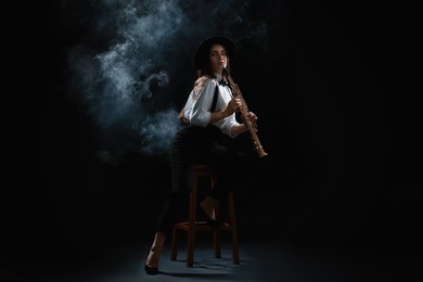 Photo of Musician playing soprano saxophone on dark background with smoke