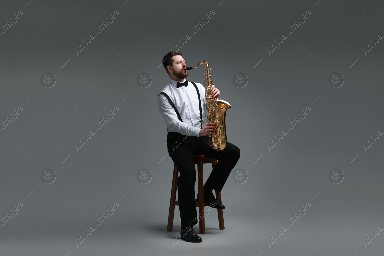 Photo of Professional musician playing saxophone on grey background