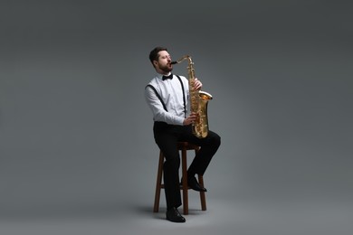 Professional musician playing saxophone on grey background