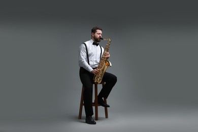 Professional musician playing saxophone on grey background