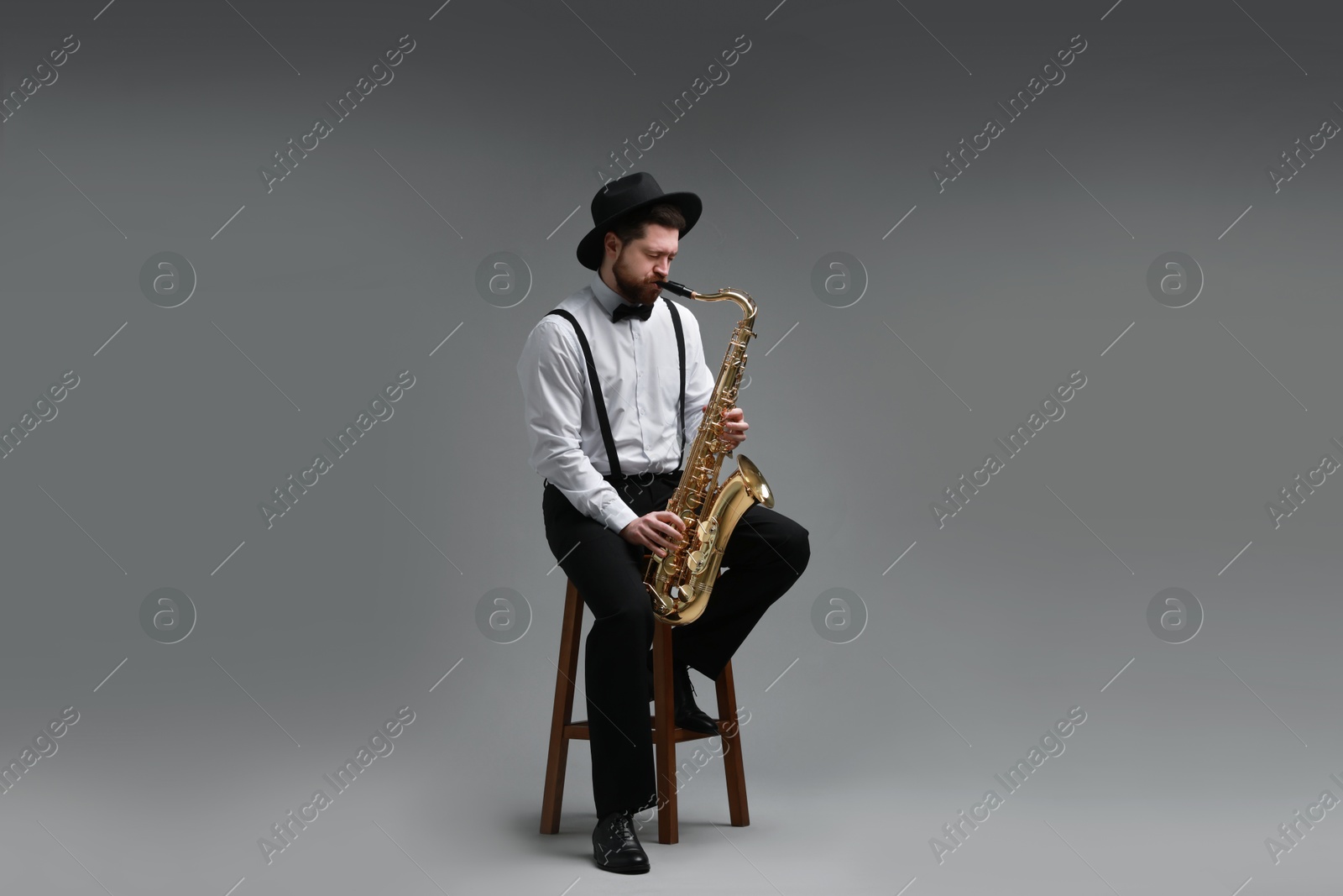 Photo of Professional musician playing saxophone on grey background