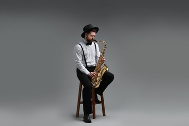 Professional musician playing saxophone on grey background