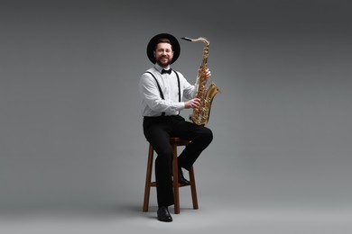 Professional musician with saxophone on grey background