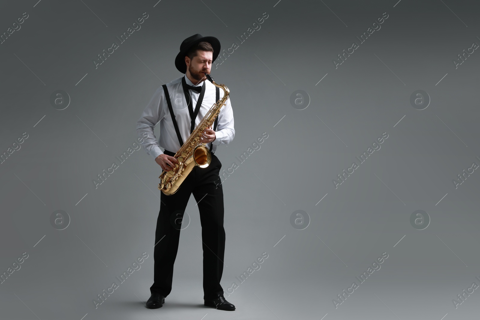 Photo of Professional musician playing saxophone on grey background