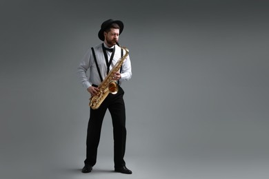 Professional musician playing saxophone on grey background