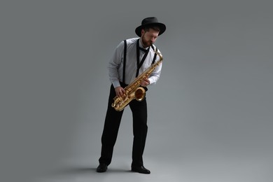 Professional musician playing saxophone on grey background