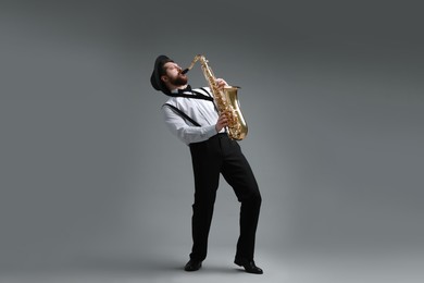 Professional musician playing saxophone on grey background