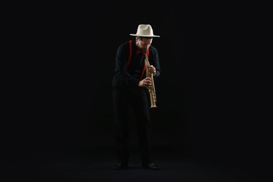 Professional musician playing soprano saxophone on black background