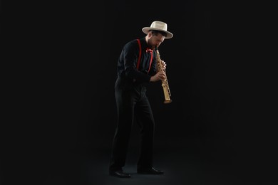 Photo of Professional musician playing soprano saxophone on black background