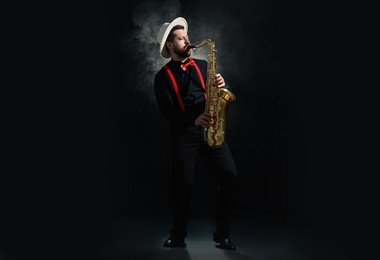 Photo of Professional musician playing saxophone on black background with smoke