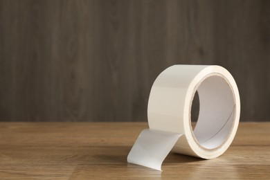 Roll of masking tape on wooden table, space for text