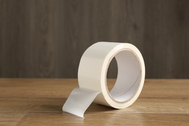 Photo of Roll of masking tape on wooden table, space for text