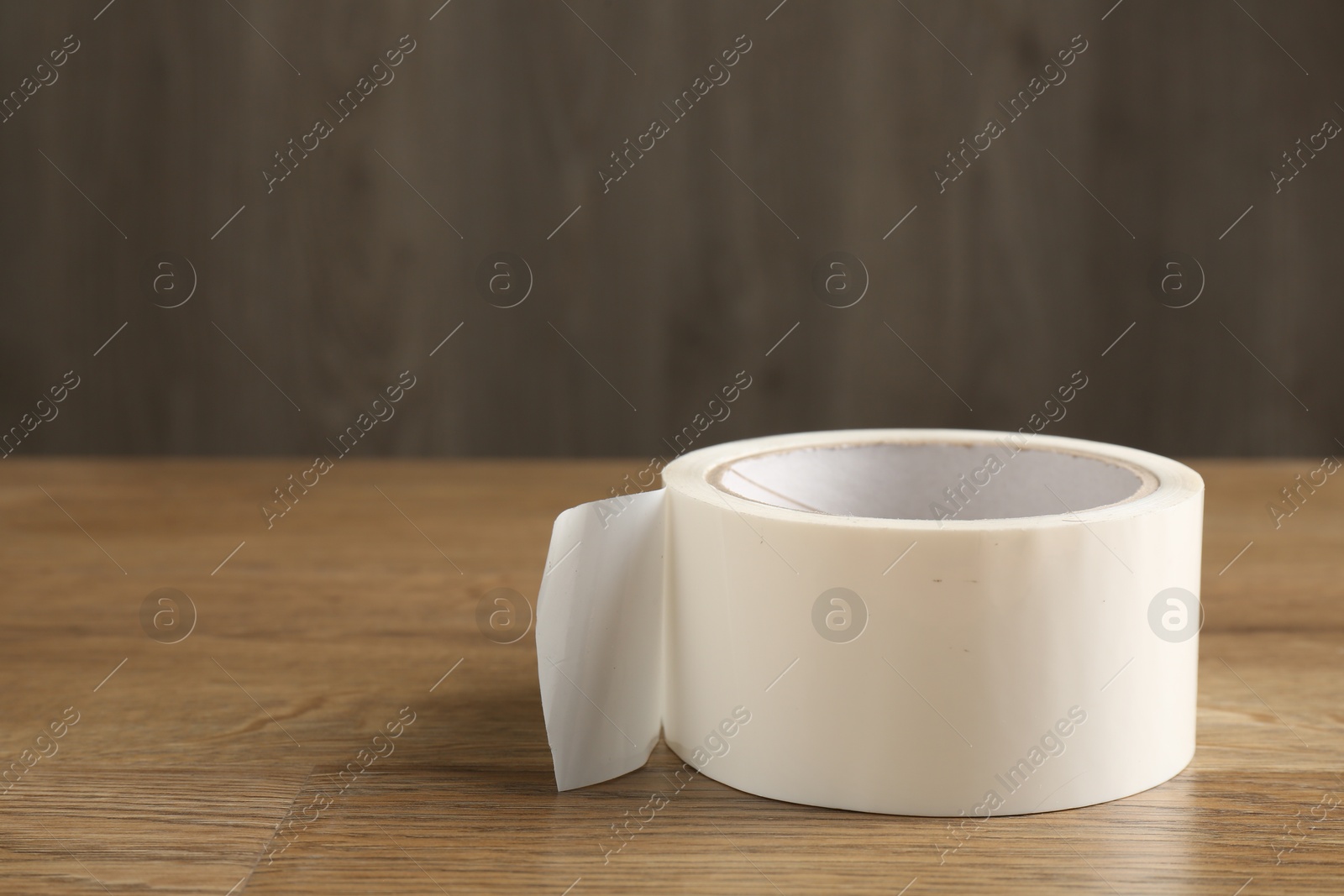 Photo of Roll of masking tape on wooden table, closeup. Space for text