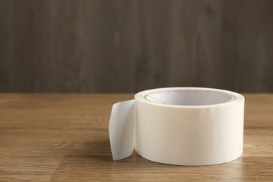 Photo of Roll of masking tape on wooden table, closeup. Space for text