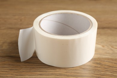 Photo of Roll of masking tape on wooden table, closeup