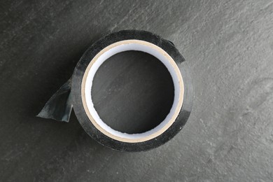 Roll of silver adhesive tape on black table, top view