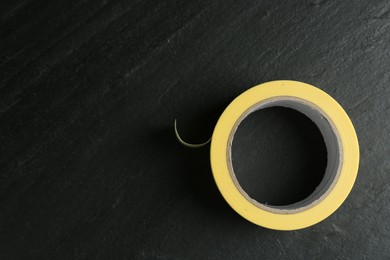 Photo of Roll of masking tape on black table, top view. Space for text