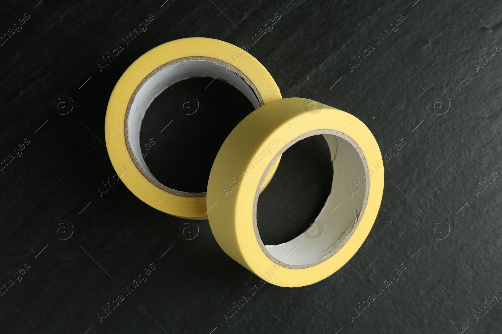 Photo of Rolls of masking tape on black table, top view