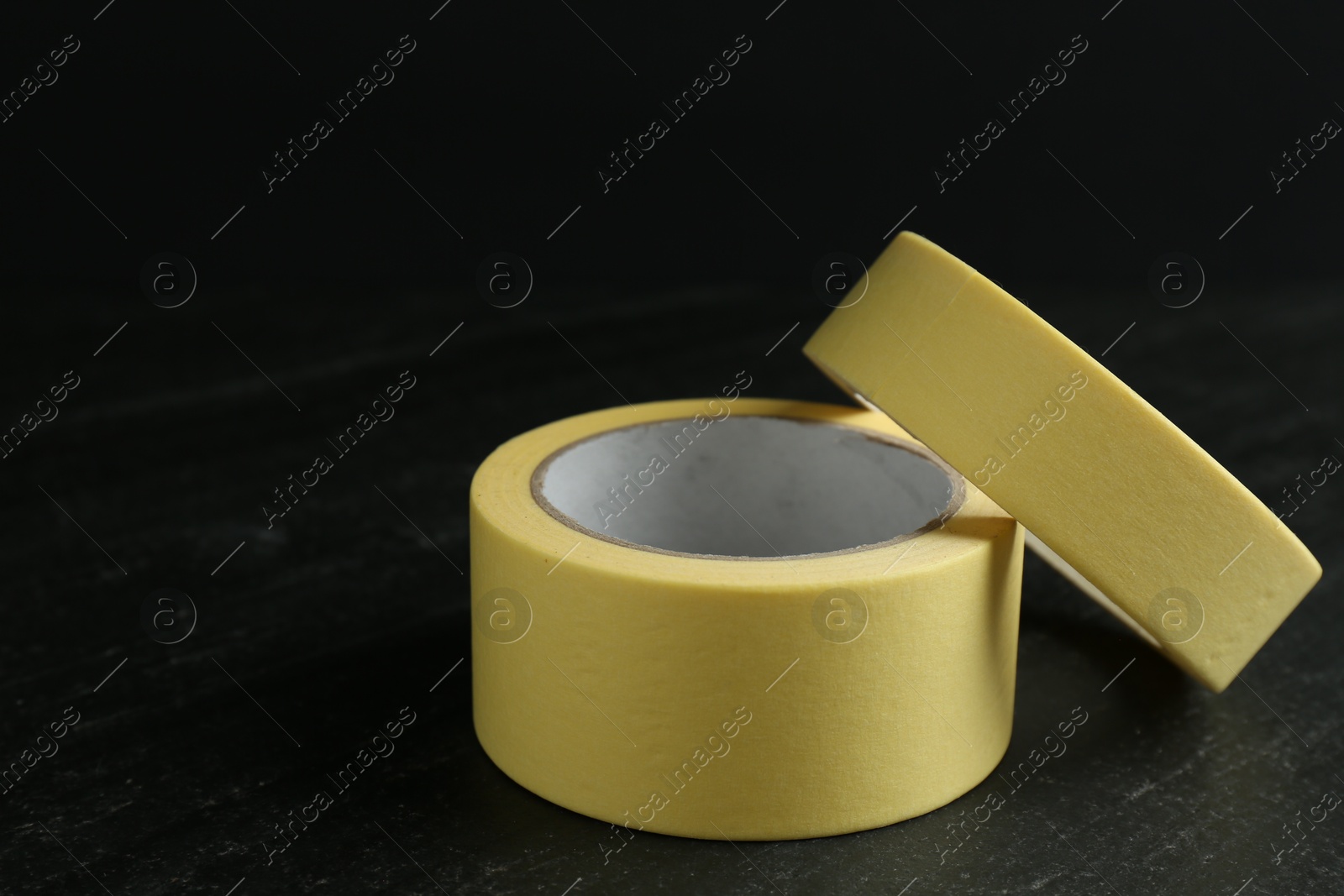 Photo of Rolls of masking tape on black table, closeup. Space for text