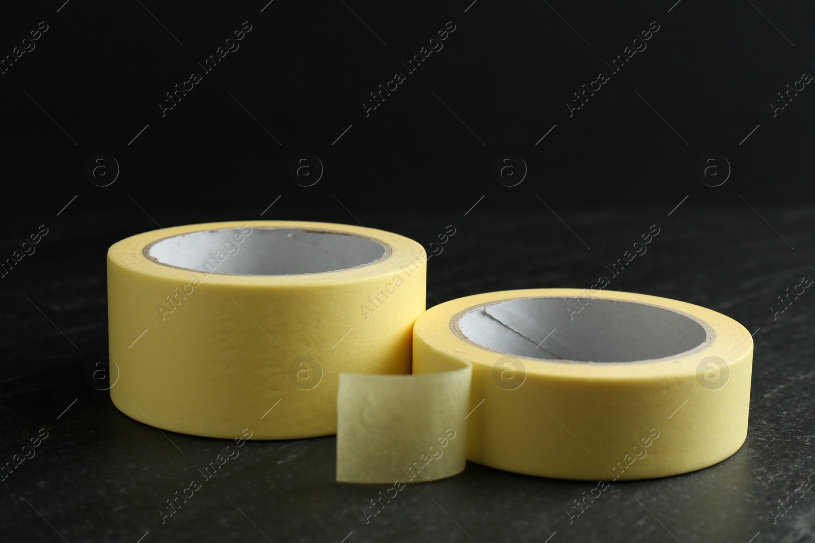 Photo of Rolls of masking tape on black table, closeup